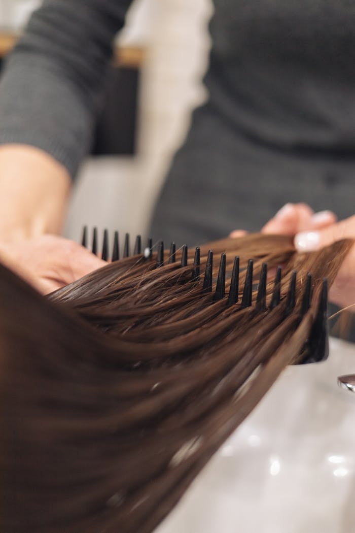 about-us-01 A hairdresser skillfully combs wet hair, focusing on smooth styling in a salon setting.
