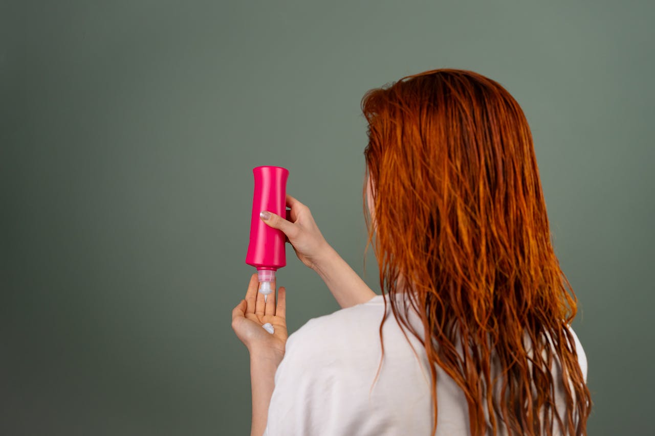 services-02 Adult woman with wet red hair applying conditioner. Hair care routine.
